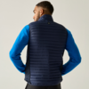 Persoon van achteren in donkerblauwe gewatteerde bodywarmer over blauw longsleeve-shirt tegen lichte achtergrond