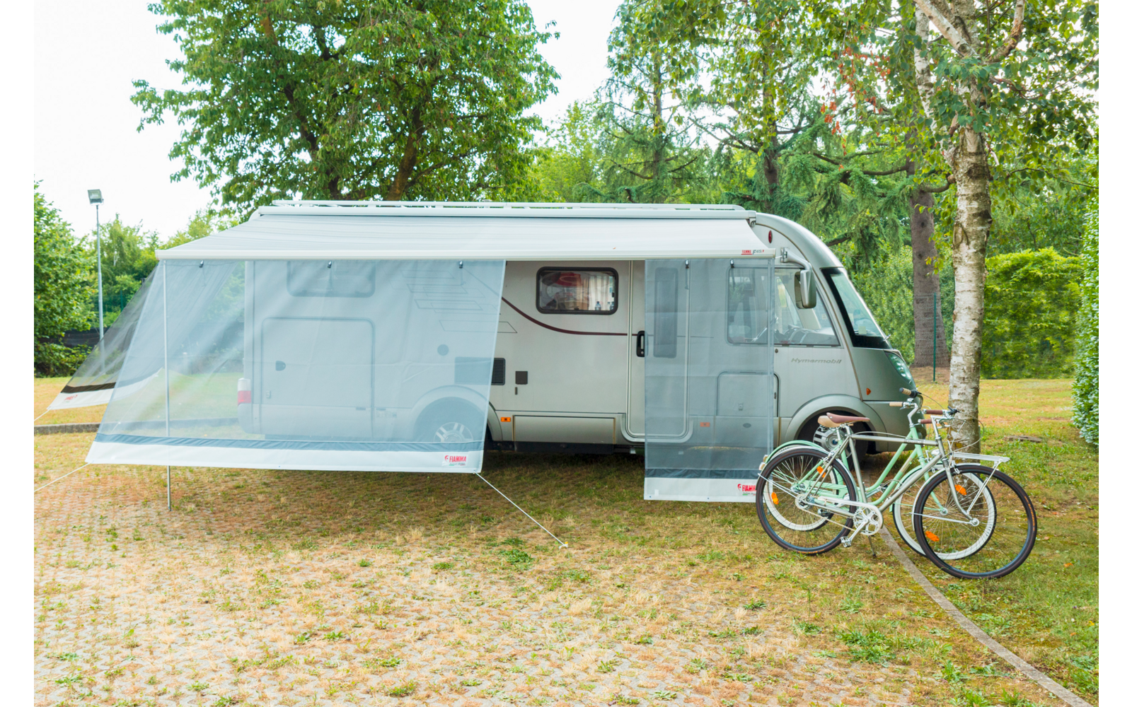 Wohnmobil mit ausgezogenem Vorzelt auf einem Platz, davor ein Fahrrad