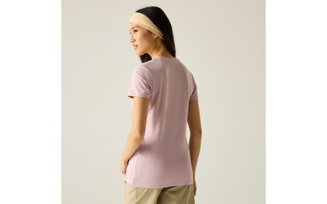 Person mit beigem Haarband und fliederfarbenem T‑Shirt, steht mit dem Rücken zur Kamera und schaut nach links vor hellem einfarbigem Hintergrund