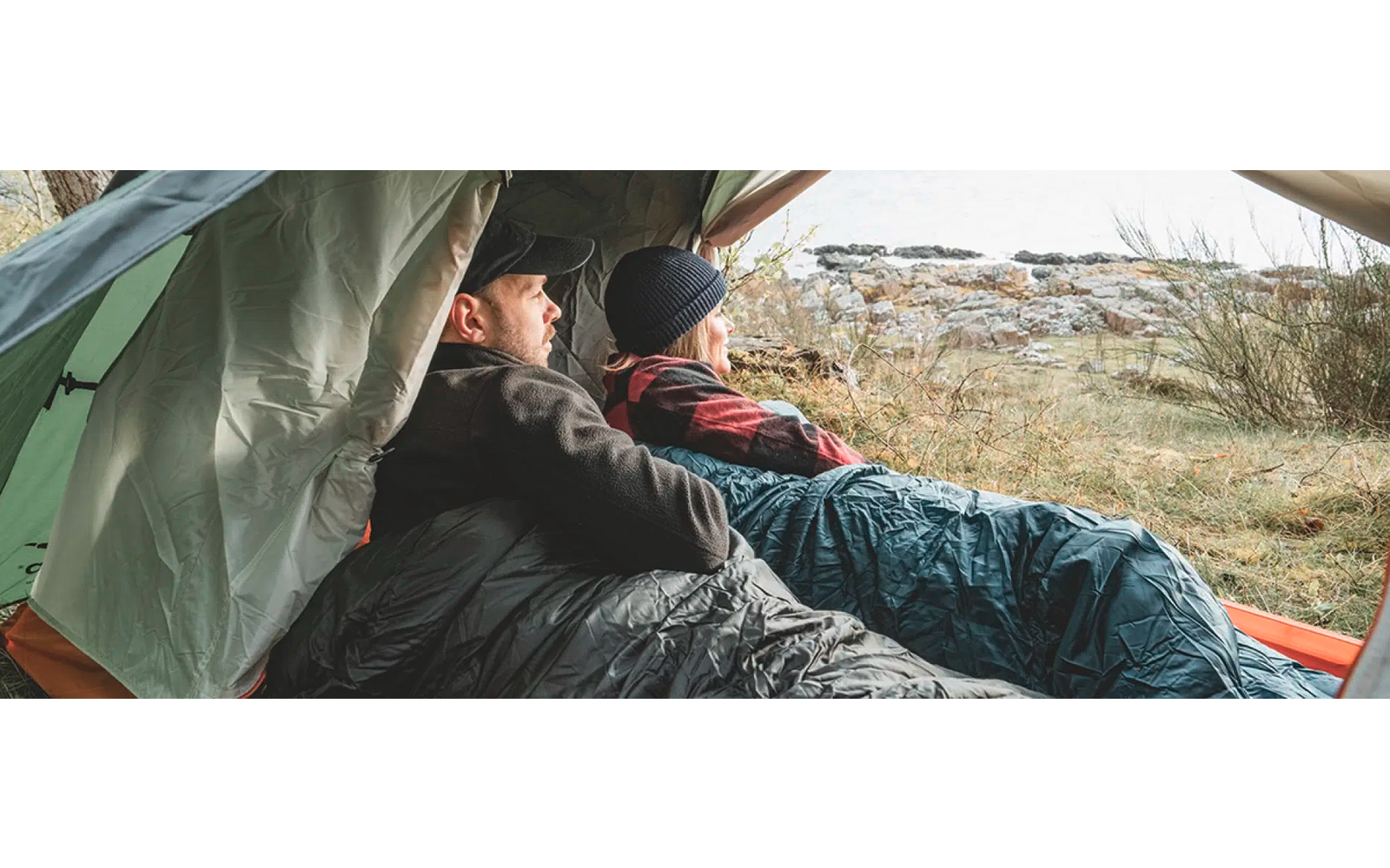 Person sitzt auf einer Steinmauer mit Blick auf Landschaft
