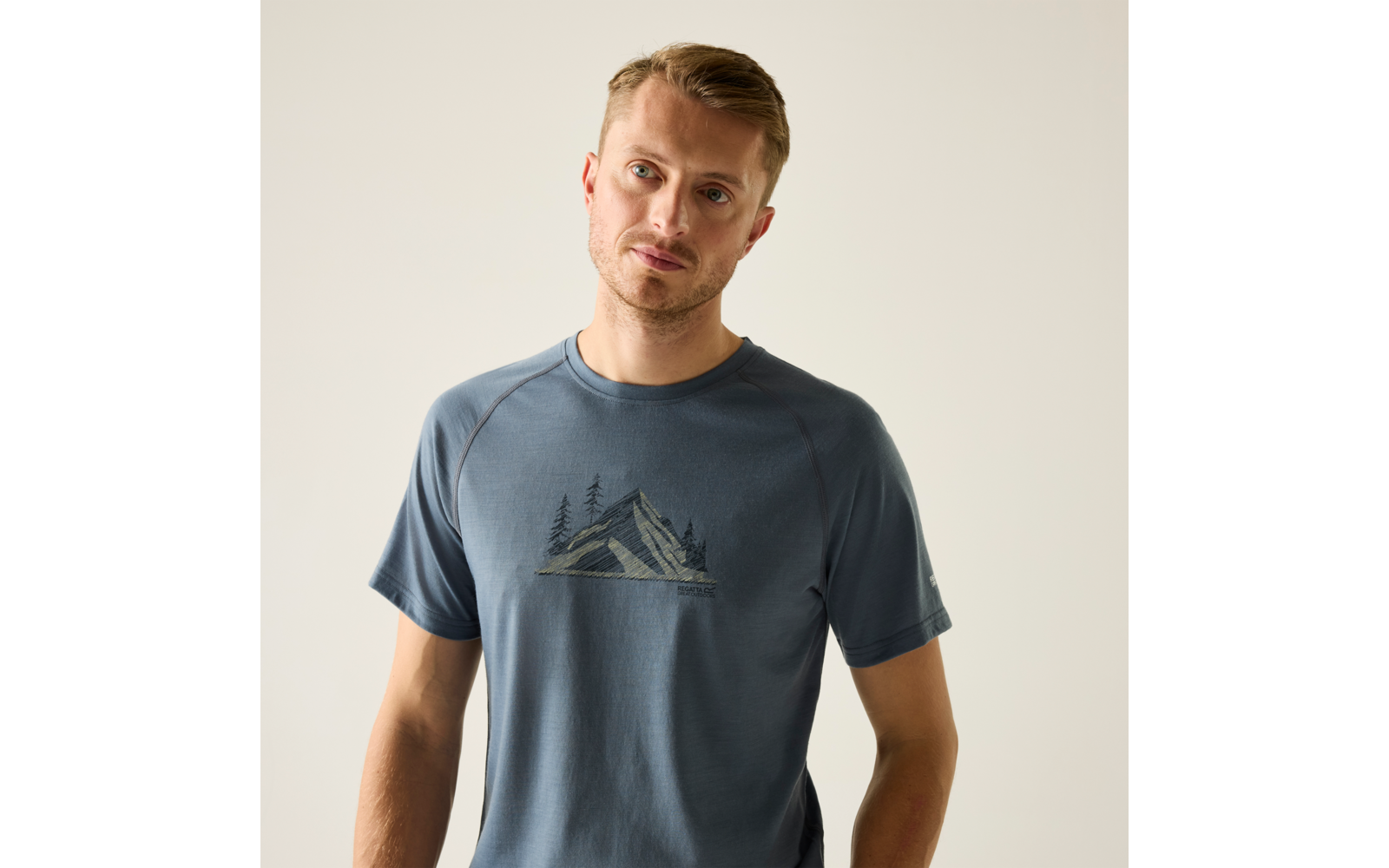 Mann mit kurzem blondem Haar, blaues T‑Shirt mit Bergmotiv, heller einfarbiger Hintergrund