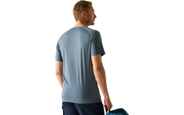 Person von hinten, trägt kurzärmeliges blaues T‑Shirt und dunkle Hose, hält eine blaue Tasche in der rechten Hand, Kopf nach rechts gedreht, heller Hintergrund