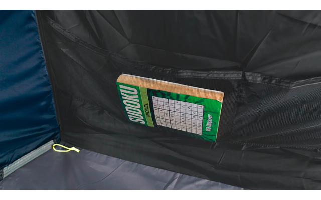 Grünes Sudoku-Heft mit sichtbarem Raster steckt in einer schwarzen Stofftasche vor dunkler Oberfläche