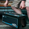 Person hebt eine schwarze Autobatterie mit beiden Händen