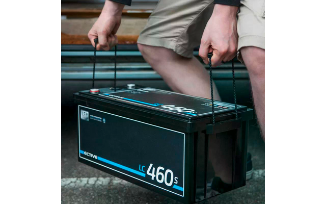 Person hebt eine schwarze Autobatterie mit beiden Händen