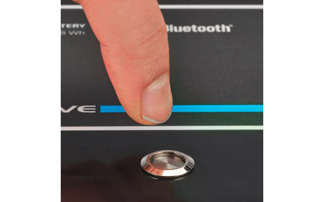 Finger berührt einen roten Knopf auf einem schwarzen Gerät mit blauer LED-Anzeige