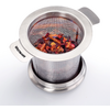 Infuseur à thé en acier inoxydable avec maille fine contenant morceaux de fruits séchés sur une petite soucoupe ; marquage "WESTMARK" sur la poignée
