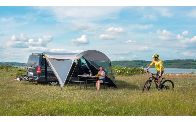 Drei Personen fahren mit Mountainbikes auf einem grünen Feld unter blauem Himmel