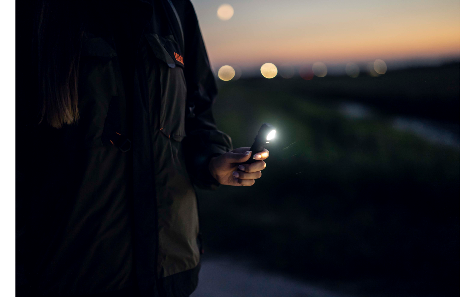 Person hält Smartphone in der Hand bei Dämmerung im Freien