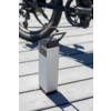 Witte rechthoekige e-bike accu op grijze grond met fietswielen op de achtergrond