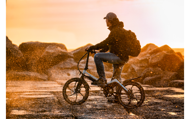 Een persoon rijdt met een fiets bij zonsondergang over oneffen terrein