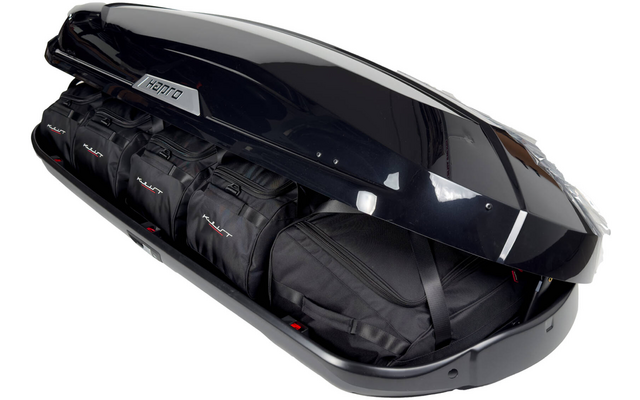 Offene schwarze Dachbox mit vier schwarzen Reisetaschen im Inneren