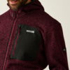 Oberkörper einer Person, die einen rot melierten Pullover mit schwarzer Brusttasche trägt