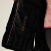 Schwarze Handschuhe mit orangefarbenen Nähten und Text auf der Innenseite