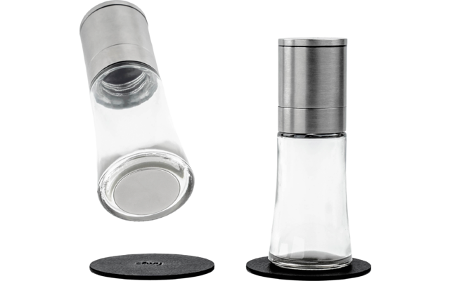 Twee specerijenmolens van glas en roestvrij staal, één staat op een zwart voetje, de andere ligt er horizontaal op