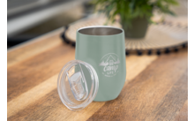 Gobelet de camping vert avec couvercle transparent sur une table en bois