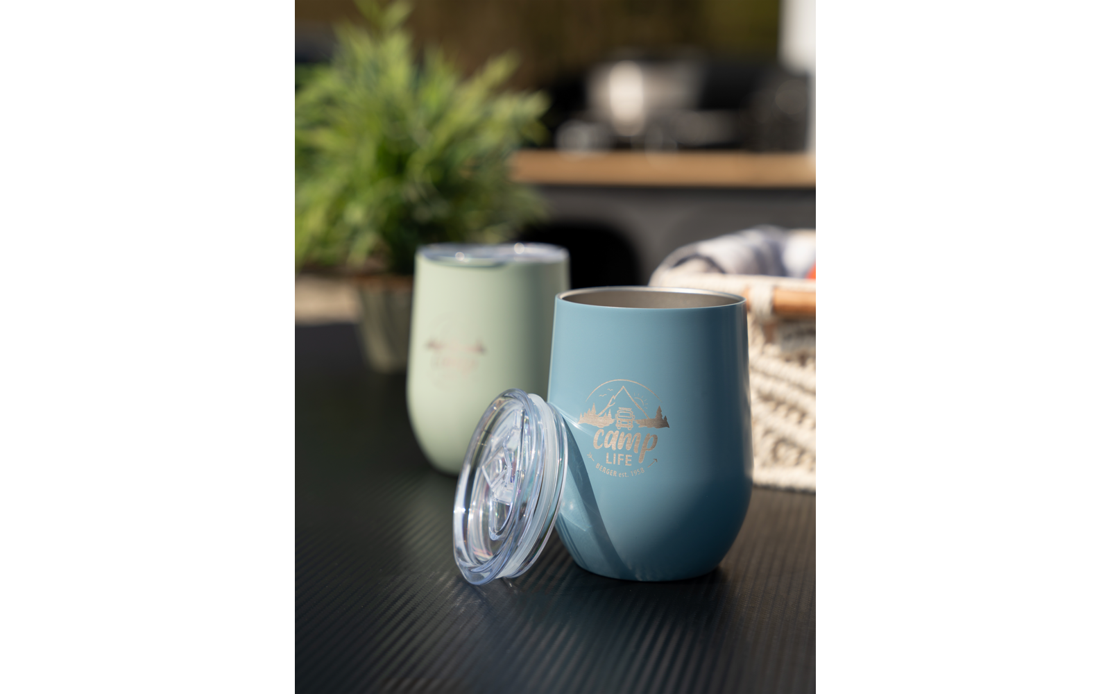 Twee thermosbekers op een tafel, planten en andere objecten wazig op de achtergrond