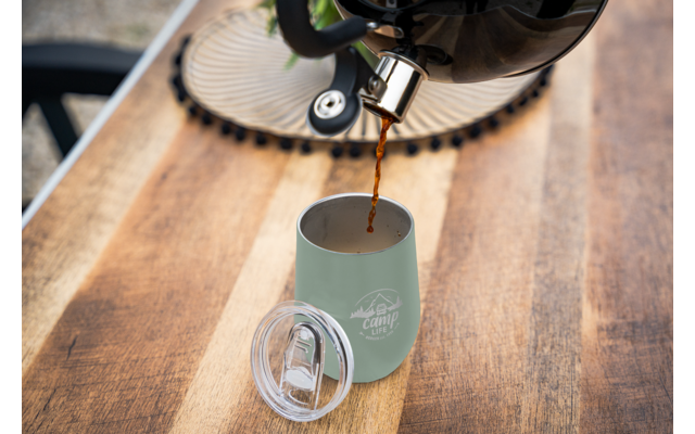 Koffie wordt vanuit een Franse pers in een groene mok op een houten tafel gegoten