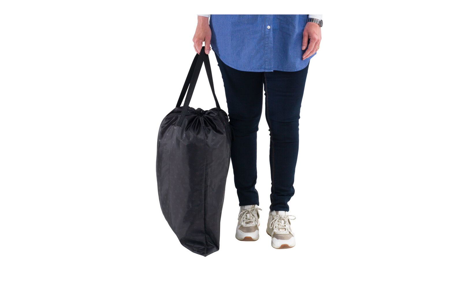 Bas du corps d'une personne debout sur fond blanc ; tient un grand sac noir à cordon par les poignées ; porte une chemise bleue, un jean foncé et des baskets blanches