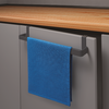 Blauwe handdoek hangt aan een greepstang aan een grijze keukenkast onder een houten aanrechtblad