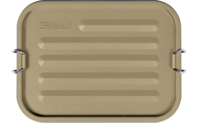 Rechthoekige goudkleurige metalen doos met afgeronde hoeken, horizontale ribbels, twee metalen zijhandgrepen en ingeslagen tekst linksboven