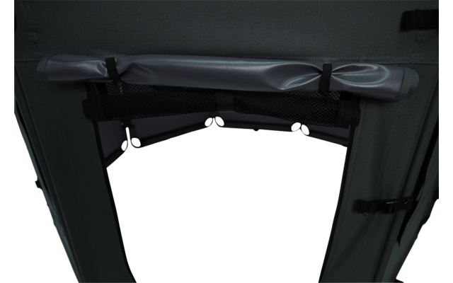 Dark gray fabric panel with a rolled-up strap at the top secured by two black clips, a mesh pocket below, side straps with buckles, and a central opening