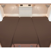Trois matelas bruns côte à côte dans un lit de camping-car avec des rideaux blancs et des stores de fenêtre