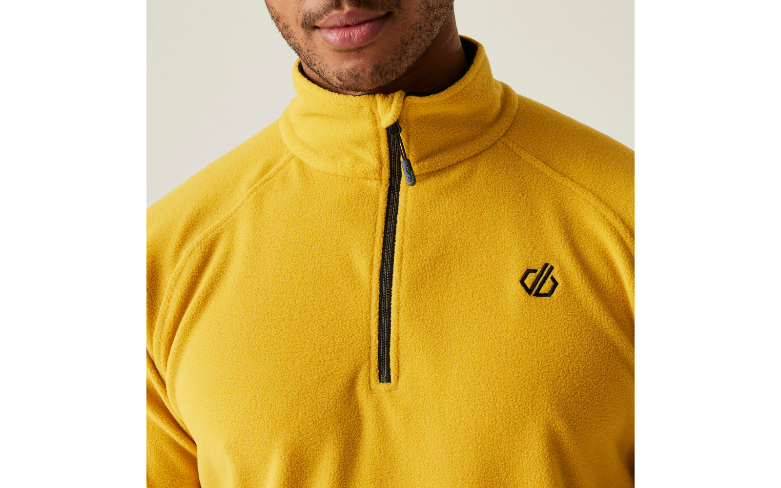 Oberkörper eines Mannes in gelbem Pullover mit Reißverschluss und einem kleinen Logo auf der Brust