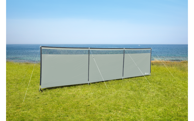 Windschutz aus grauem Stoff auf grünem Gras am Meer