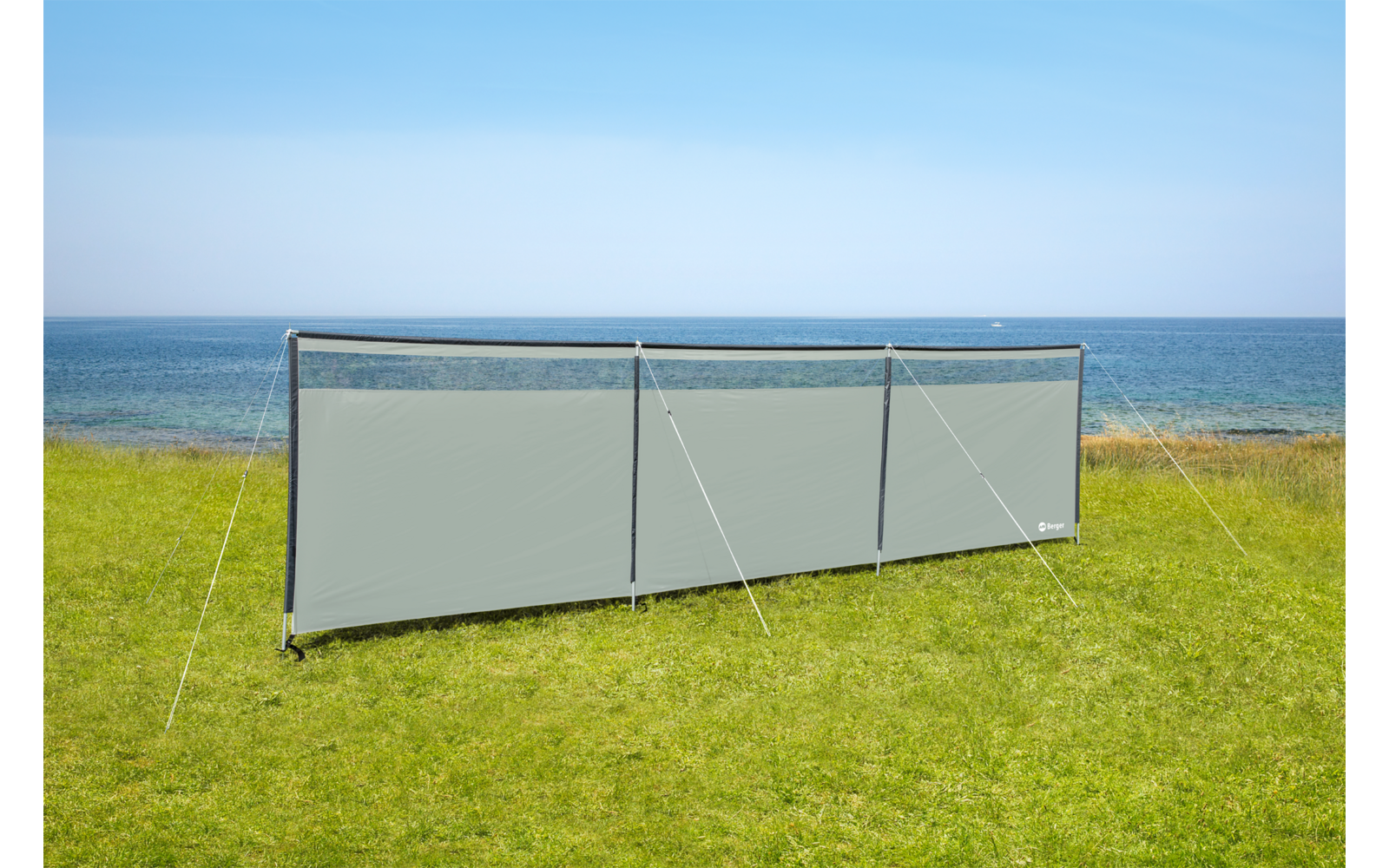 Windschutz aus grauem Stoff auf grünem Gras am Meer