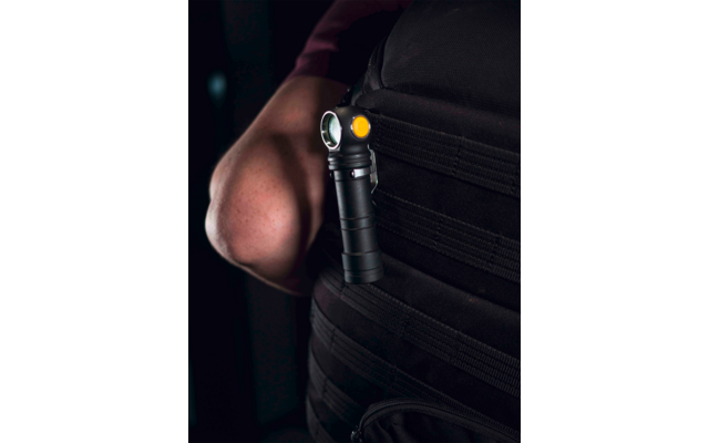 Hand hält Taschenlampe an seitlicher Tasche einer dunklen Weste
