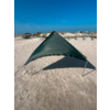 Grüne, dreieckige Plane auf zwei Stangen auf sandigem Strand; Dünen, Gebäude und blauer Himmel im Hintergrund