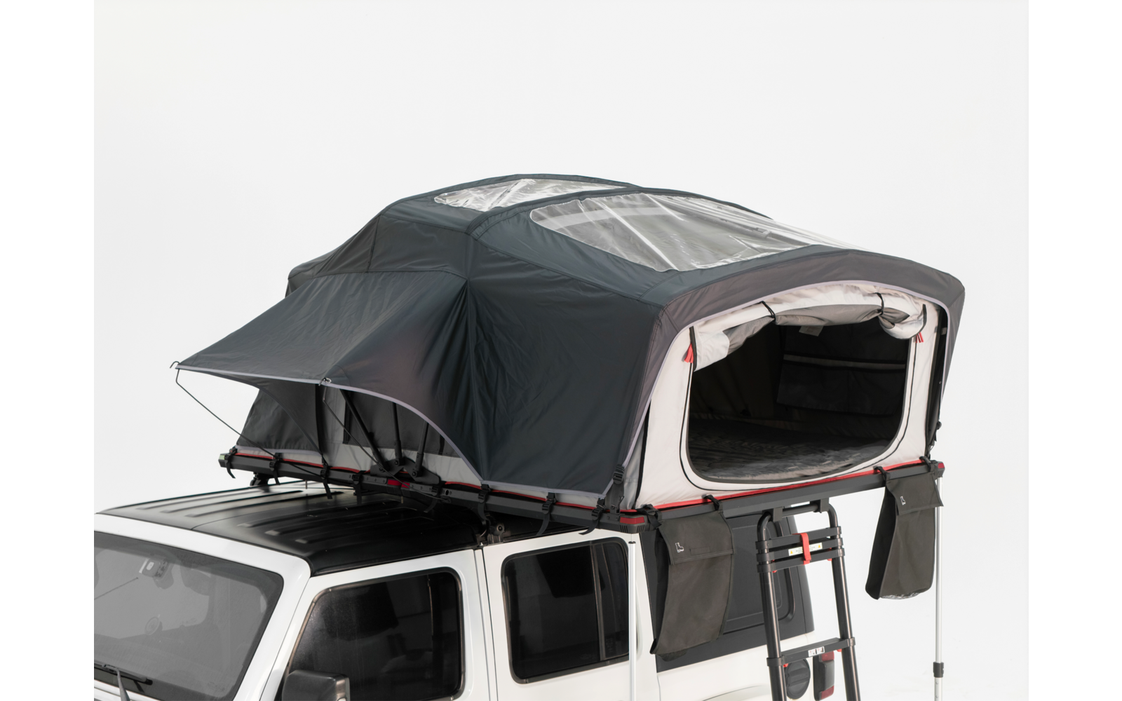 Aufgeklapptes dunkles Dachzelt auf einem weißen Geländewagen, vordere Öffnung offen und Leiter angebracht
