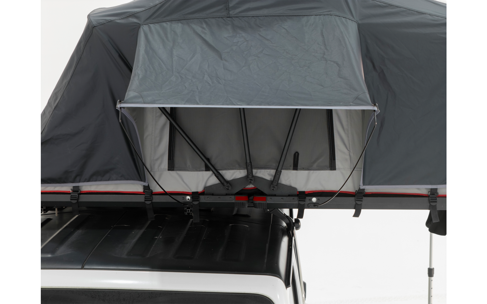 Aufgeklapptes Dachzelt mit offenem Frontfenster und grauer Stoffabdeckung, montiert auf dem Dach eines weißen Fahrzeugs