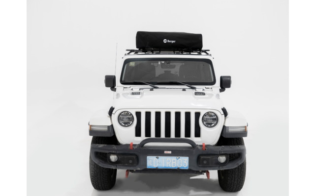 Frontaufnahme eines weißen Geländewagens vor weißem Hintergrund. Schwarzer Dachträger mit schwarzer Tasche, runde Scheinwerfer, schwarze Stoßstange, sichtbares blaues Kennzeichen