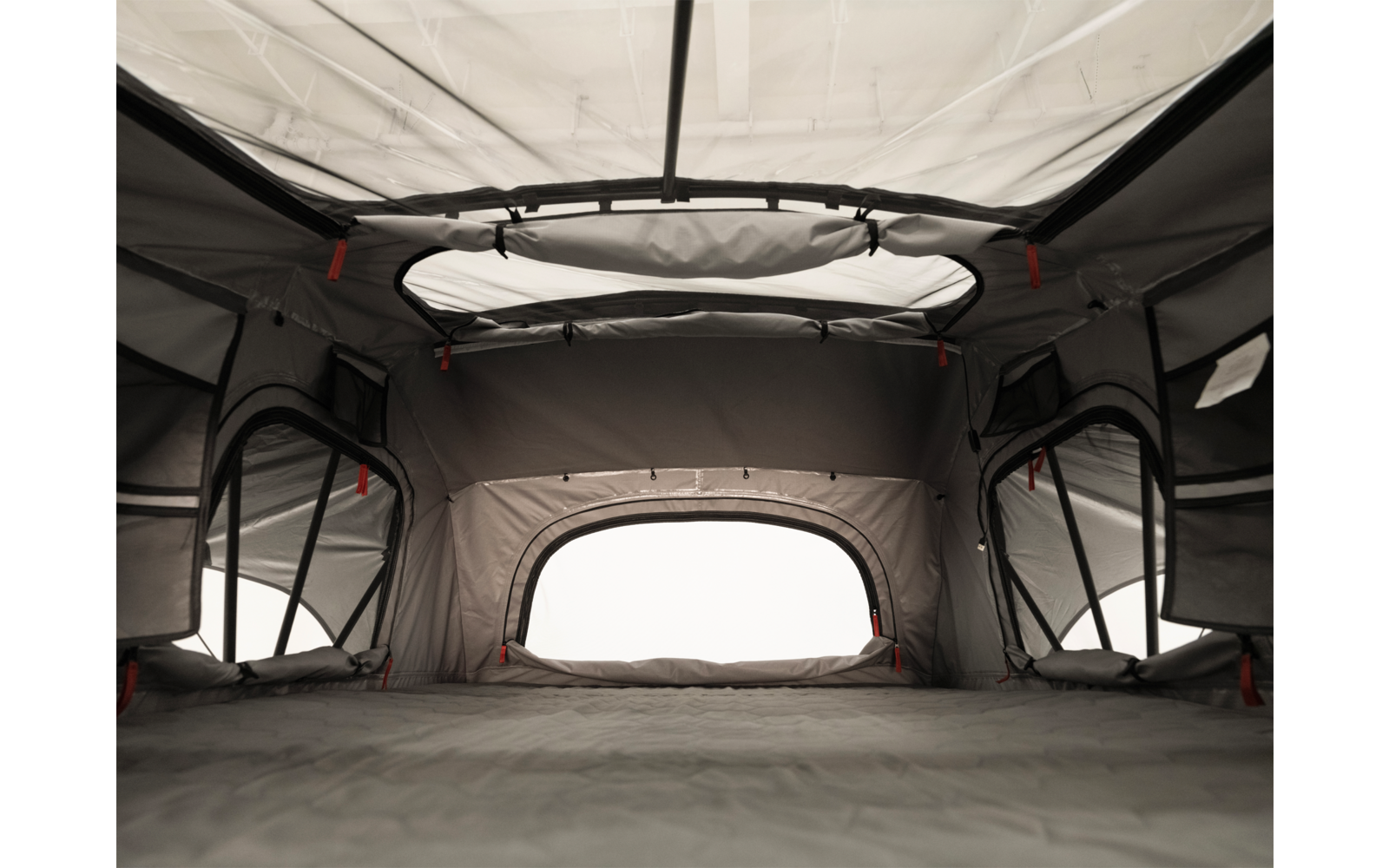 Innenansicht eines grauen Zeltes mit runder Dachöffnung, Stoffwänden, vier Fenstern mit Netz und einer flachen Bodenfläche