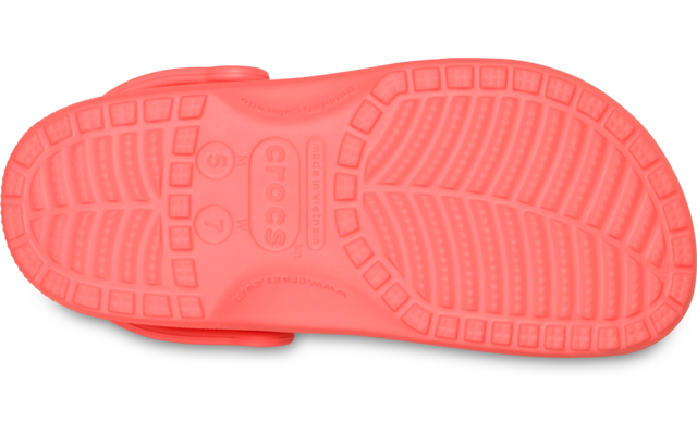 Unterseite einer korallfarbenen Schuhsohle mit Profilmuster und seitlich sichtbarem Riemen