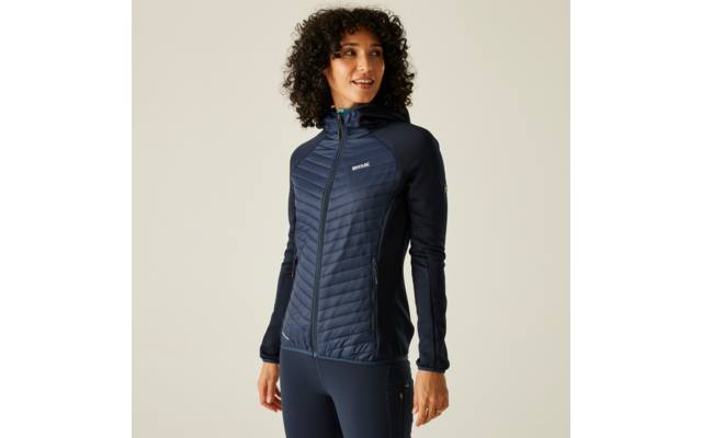 Person mit dunklen lockigen Haaren trägt marineblaue gesteppte Kapuzenjacke und passende Leggings, steht vor hellem einfarbigem Hintergrund, Blick leicht nach rechts, Hände seitlich