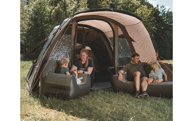 Zwei Personen sitzen vor einem offenen, kahfig geformten Zelt im Grünen