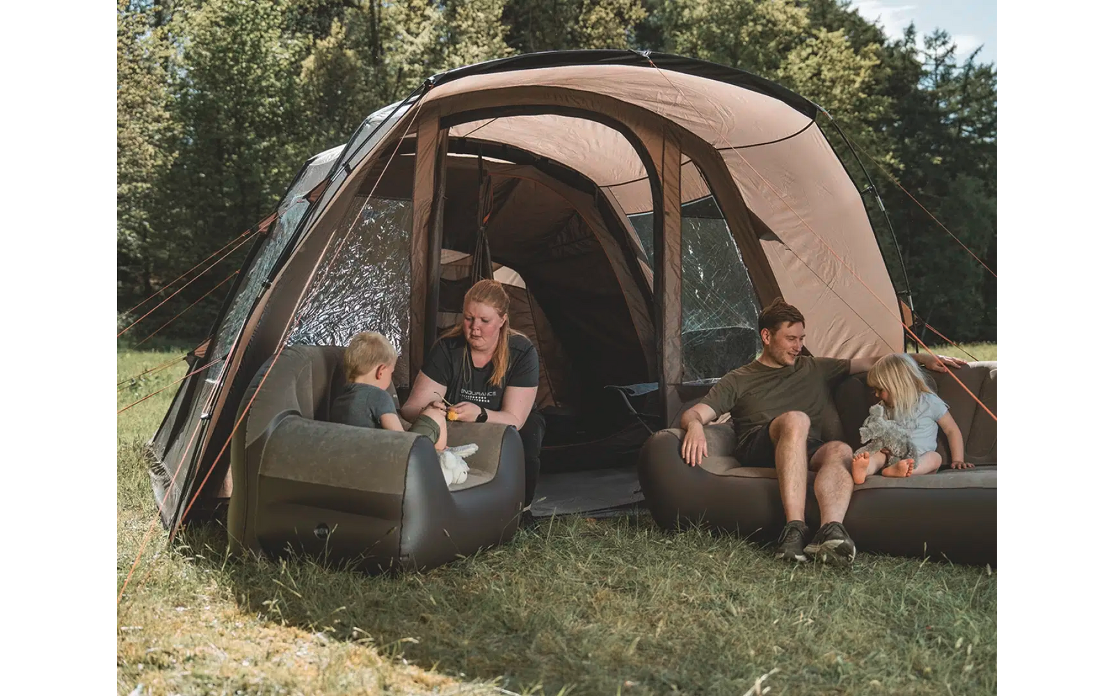 Zwei Personen sitzen vor einem offenen, kahfig geformten Zelt im Grünen