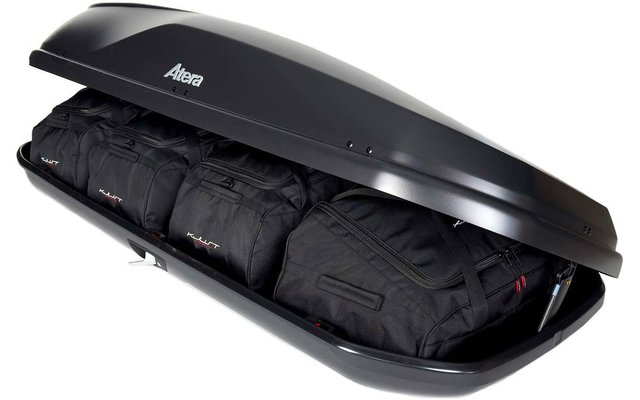 Geöffnete schwarze Dachbox mit sichtbarem Atera-Logo, drei schwarze Reisetaschen im Inneren