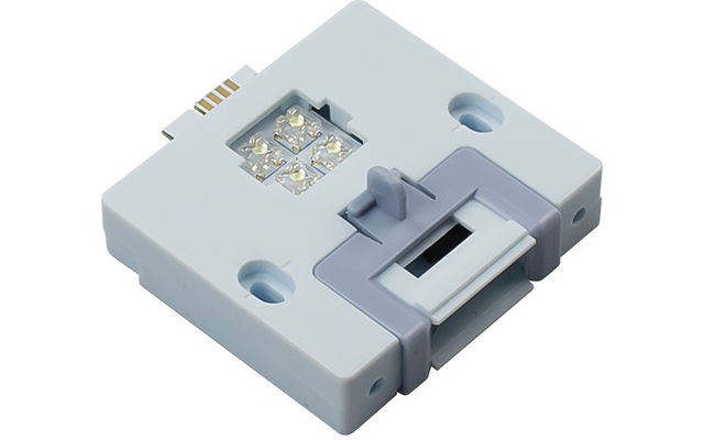 Rechteckiges weiß-graues Gehäuse mit vier kleinen LEDs in quadratischer Anordnung, zwei Befestigungsbohrungen, seitlichem Steckkontakt und grauem Clip