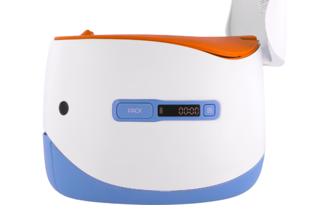 Weißes rundliches Gerät mit orangefarbener Klappe oben, blauem Sockel, blauem Knopf mit Aufschrift 'PACK' und kleinem digitalen Display '00:00'