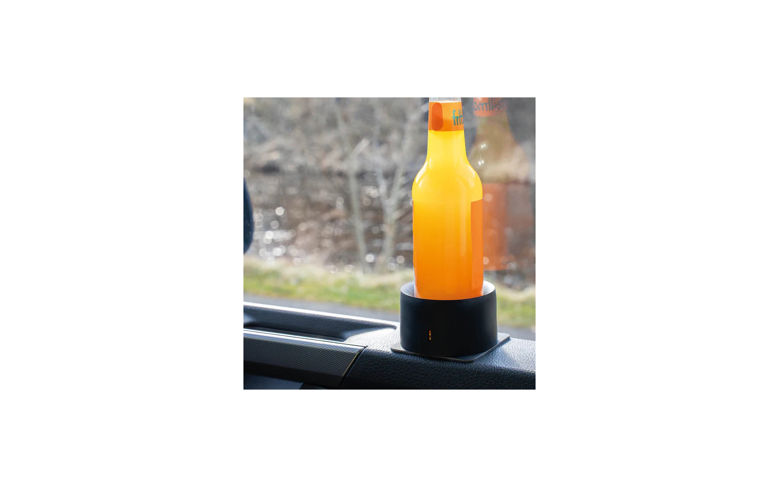 Una botella naranja está colocada en un soporte negro dentro de un coche