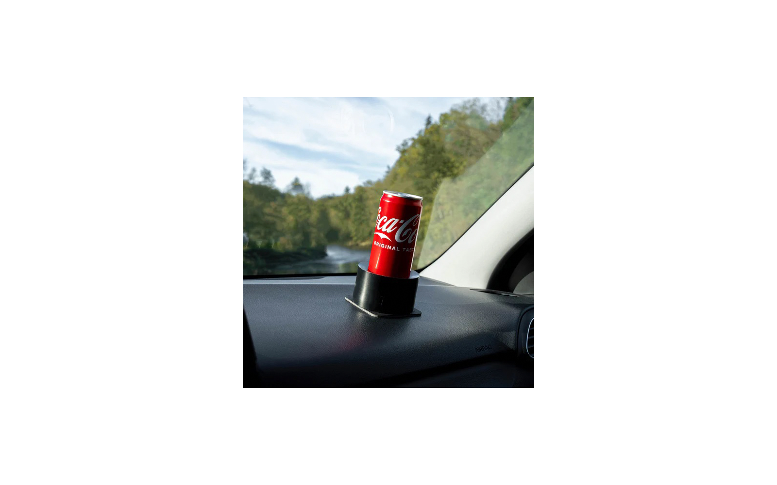 Eine rote Coca-Cola-Dose steht in einem Becherhalter im Auto