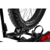 Rueda de bicicleta con neumático de tacos situada en un soporte de plástico de un portabicicletas trasero, luz trasera roja del vehículo visible abajo a la derecha