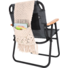 Schwarzer Klappstuhl mit einem Häkelsitzbezug in Beige und taschenartiger Ablage mit Stiften und Notizblock