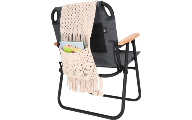 Schwarzer Klappstuhl mit einem Häkelsitzbezug in Beige und taschenartiger Ablage mit Stiften und Notizblock