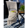 Bolsa de macramé con revistas colgada en una silla al aire libre