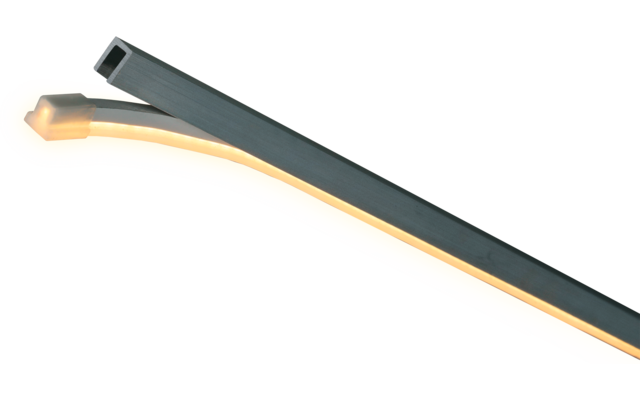 Barre métallique étroite gris foncé à côté d'une bande lumineuse flexible et translucide diffusant une lumière jaune chaude sur fond blanc
